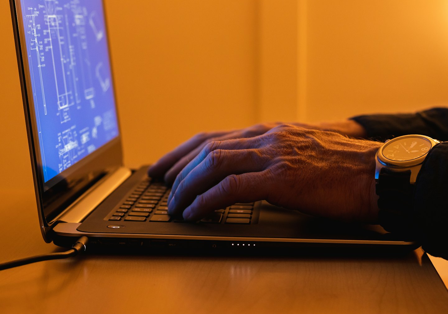 Mani che digitano su un laptop con progetti architettonici sullo schermo.