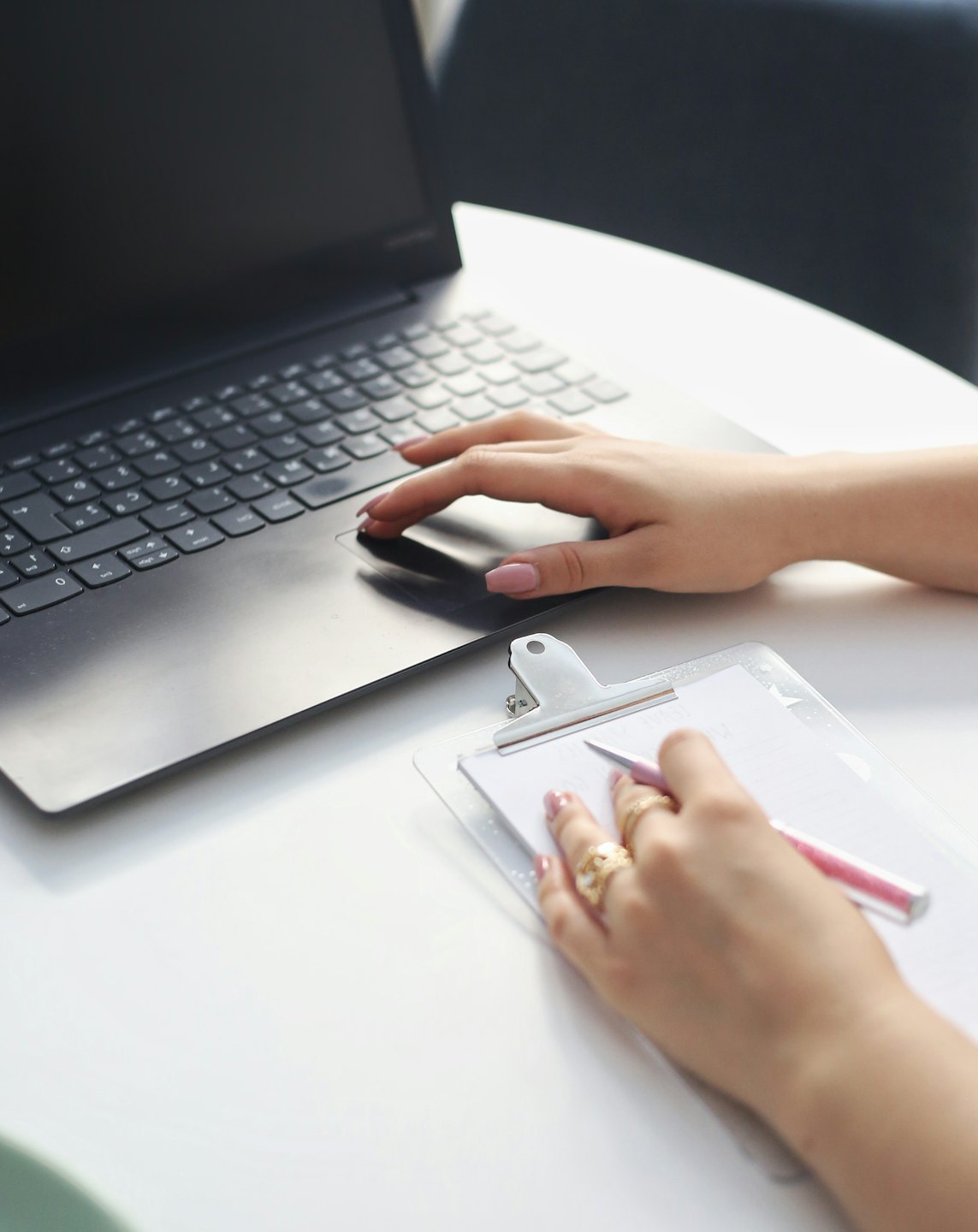 Mani che scrivono su un computer portatile e su un blocco note.